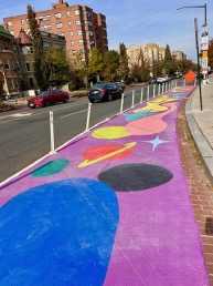 Colorful painted bike or pedestrian lane with bright circular shapes along a city street.